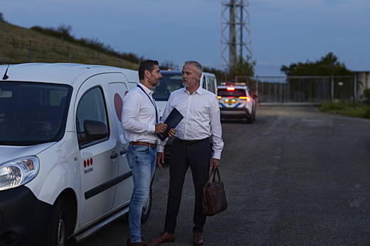 Två män står och pratar framför en Securitasbil