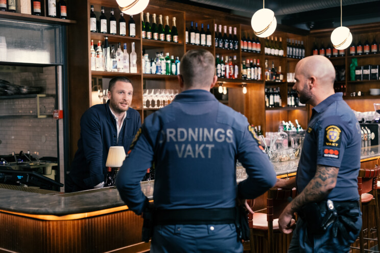 Restaurangmedarbetare pratar med väktare vid bardisk