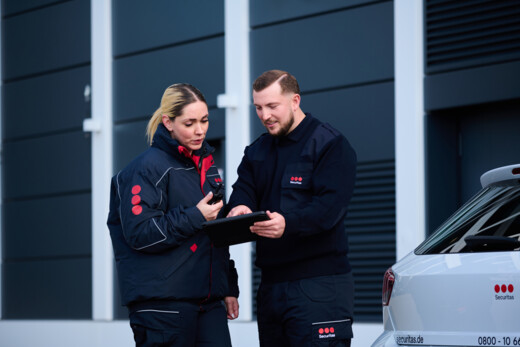 Personal Securitas utilizând o tabletă pentru coordonarea activităților de securitate în exteriorul unei clădiri comerciale.
