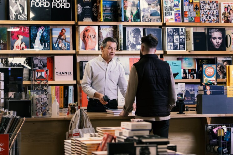 Mandlig ekspedient ekspederer en kunde i en boghandel