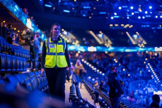 Securitasova zaštitarka u žutom prsluku promatra navijače na nogometnom stadionu