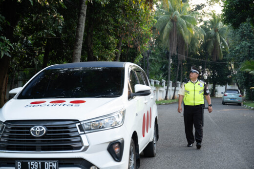 Securitas guard standing next to at a mobile patrol car near a house