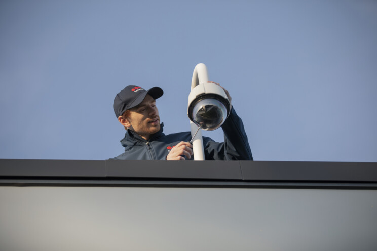 Pracownik firmy ochroniarskiej montuje kamerę CCTV.