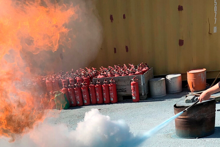 En Securitas-vagt slukker en brand med en brandslukker til et brandbekæmpelseskursus hos Securitas