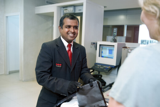 Security officer assisting a visitor at a reception desk in a modern office environment, supporting access control and visitor management procedures.