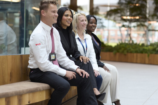 Security officer and office employees seated in a modern workplace reception or breakout area, highlighting a welcoming and secure business environment.