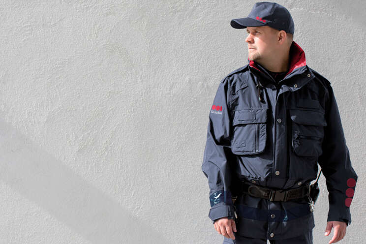 Securitas sikkerhedsvagt i uniform, der står foran en grå mustensvæg