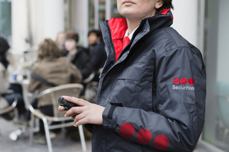 Kvindelig Securitas-medarbejder står udendørs på et butisktrøg