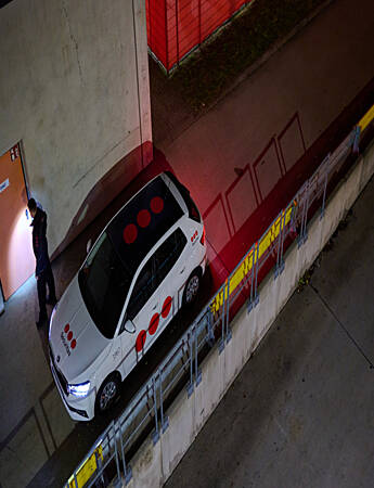 Securitas mobile security officer in a marked patrol car checking the doors of a business premises at night in Ireland