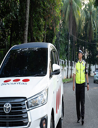 A security guard in a baseball cap behind the wheel of a company vehicle; Mobile patrol monitoring the safety of the area in urban conditions