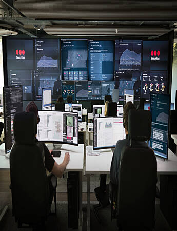 Securitas Risk Intelligence Center featuring multiple screens displaying live data, with intelligence analysts actively monitoring operations.