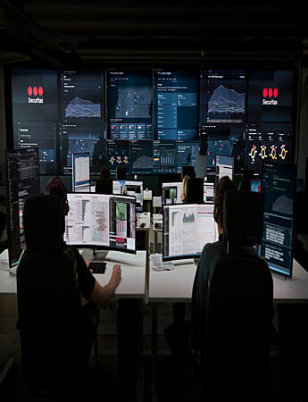 Fire Securitas-operatører overvåker kameraer og hendelser på skjermer i operasjonssentralen.