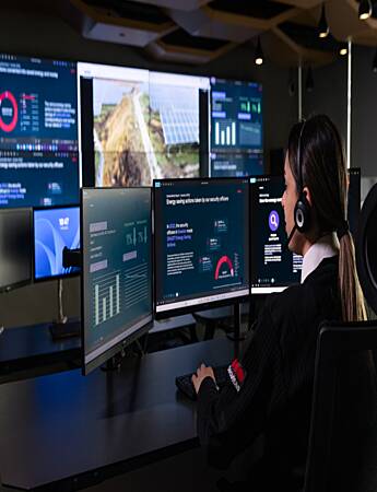Security Operations Center operator monitoring live security data, surveillance feeds, and incident alerts across multiple screens.