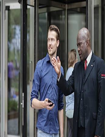 Male Securitas receptionist assists a male visitor in an office building. 