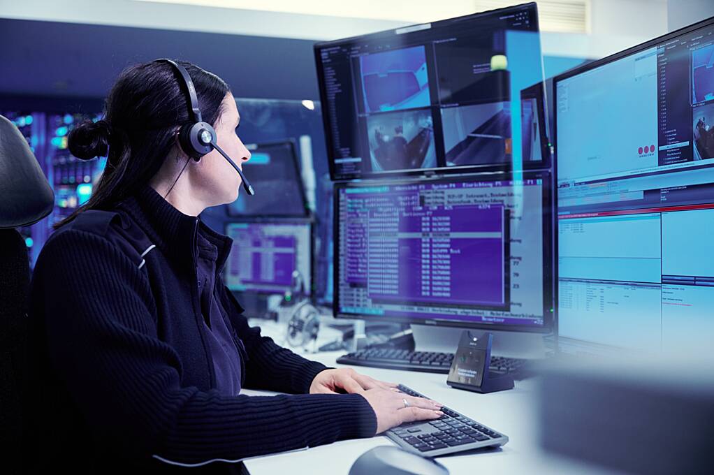 Operatorul SOC monitorizând evenimente de securitate pe mai multe ecrane într-un centru de control.