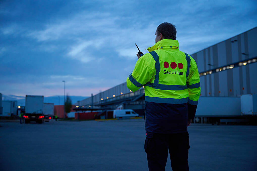 Securitas security officer monitoring activity at a logistics facility and distribution center during evening operations.