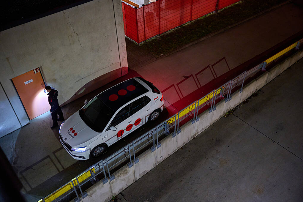 Securitas patrol officer walking the client site perimeter, with a Securitas-branded car parked outside
