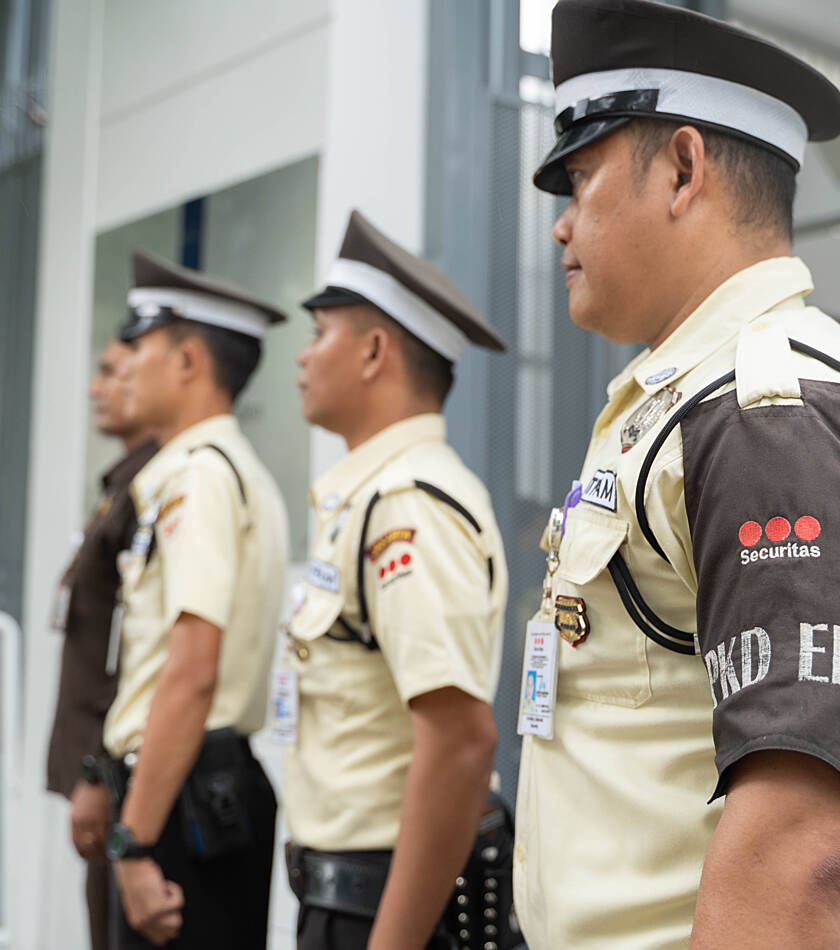 Securitas employees standing and seated at a workstation, looking over papers during a team discussion.