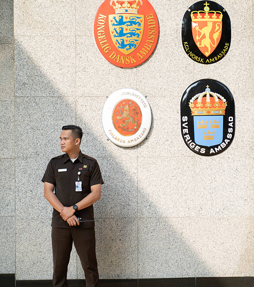 Securitas employee standing in a security operations centre, holding a tablet with multiple monitoring screens displayed behind.