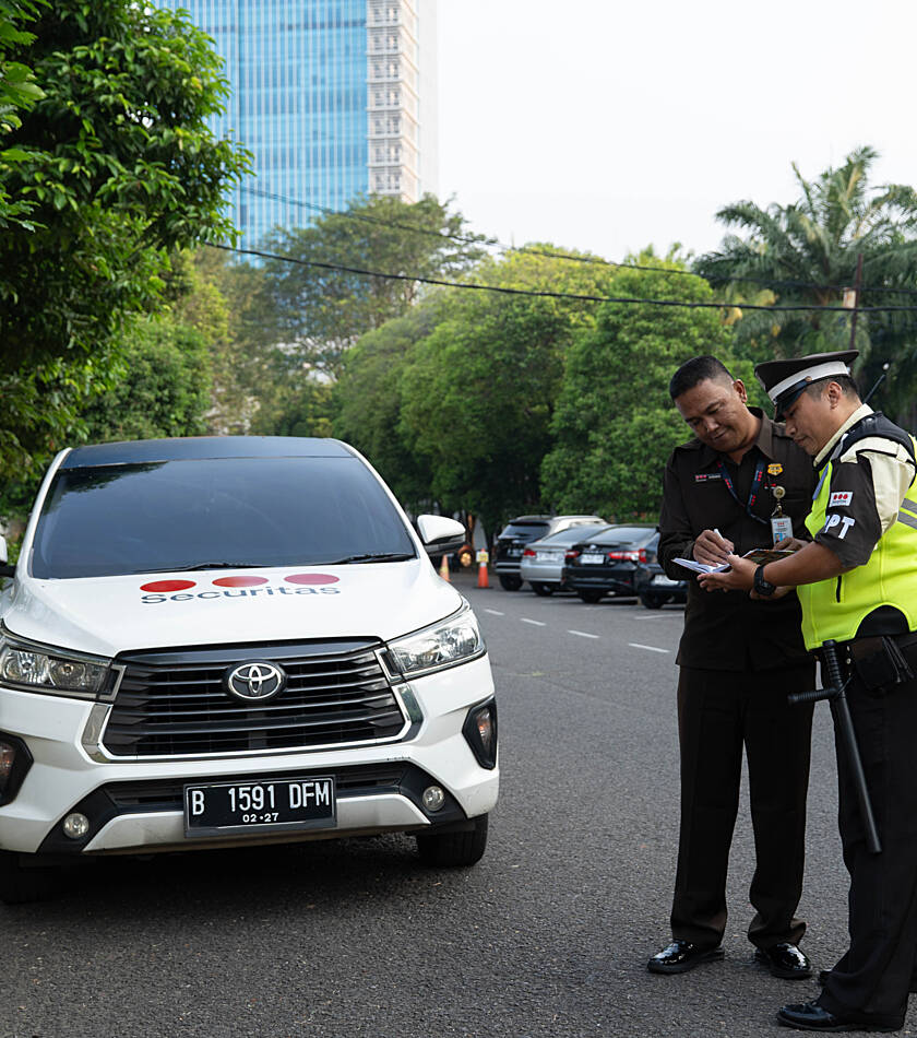 Security guard at patrol car in front of glass office building