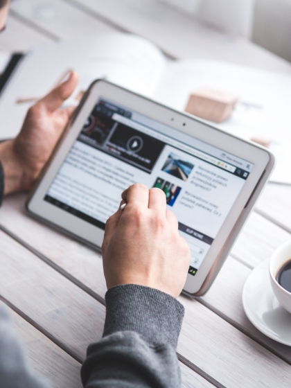 A man going through a website with a cup of coffee.