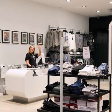 Fashion store with cashier waving to camera