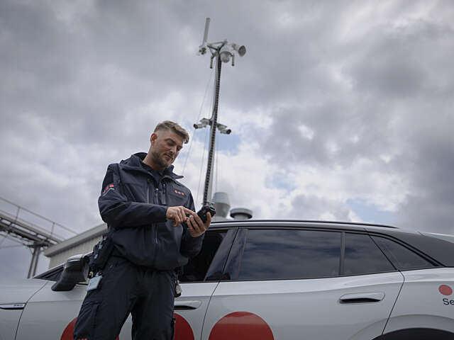 Patrolling Securitas security guards checks the burglary alarm standing infront of the white vehicle