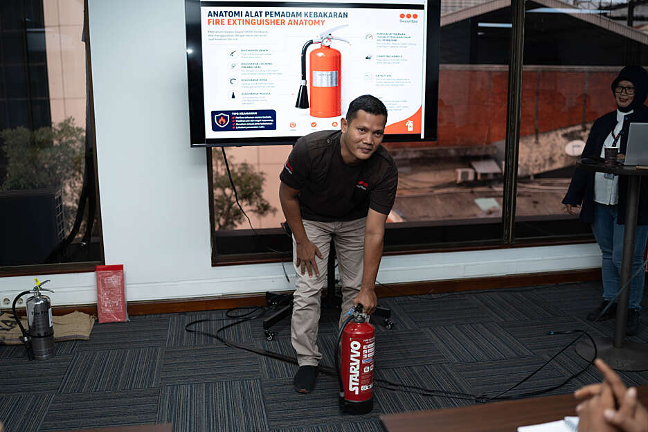 Securitas-led fire safety drill with a man participating in a firefighting training exercise outside a commercial office building.