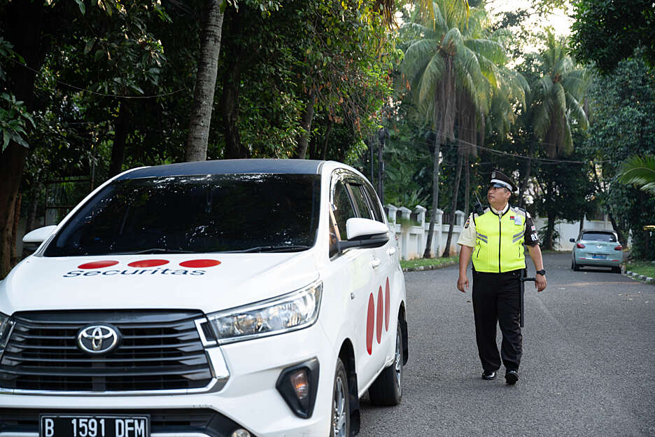 Securitas guard standing next to at a mobile patrol car near a house