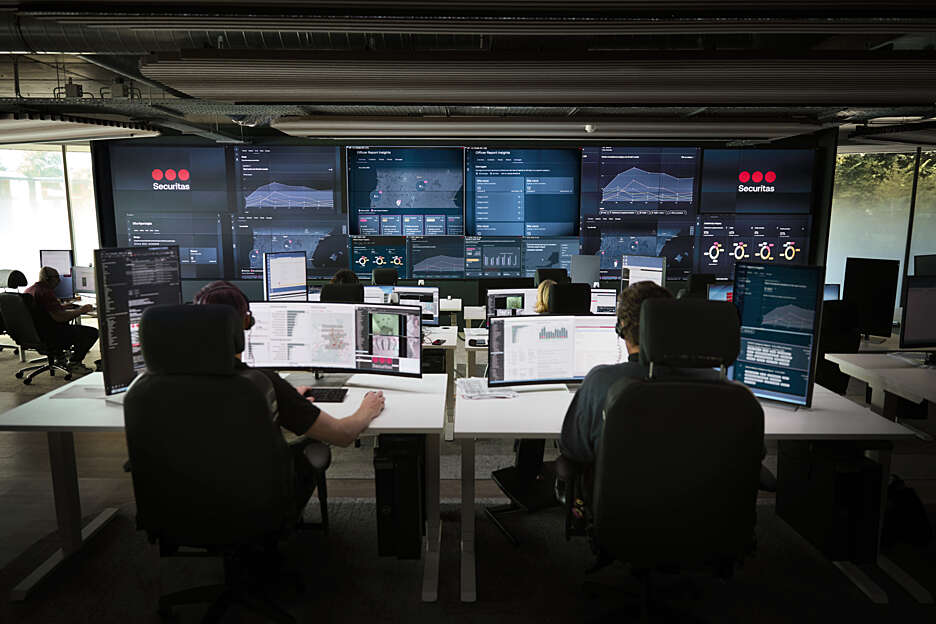Securitas Risk Intelligence Center featuring multiple screens displaying live data, with intelligence analysts actively monitoring operations.
