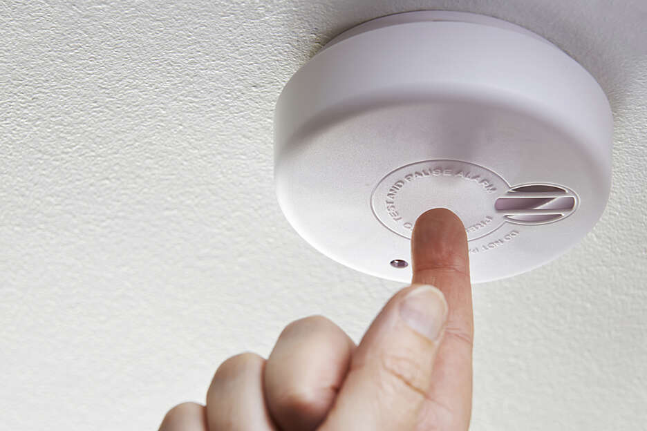 Employee testing a smoke alarm detector