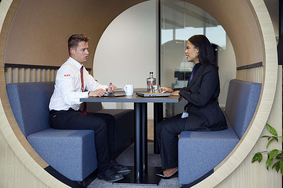 1 uniformierter Securitas Mitarbeiter und eine Mitarbeiterin sitzen in einem Besprechungskobel und unterhalten sich mit 
