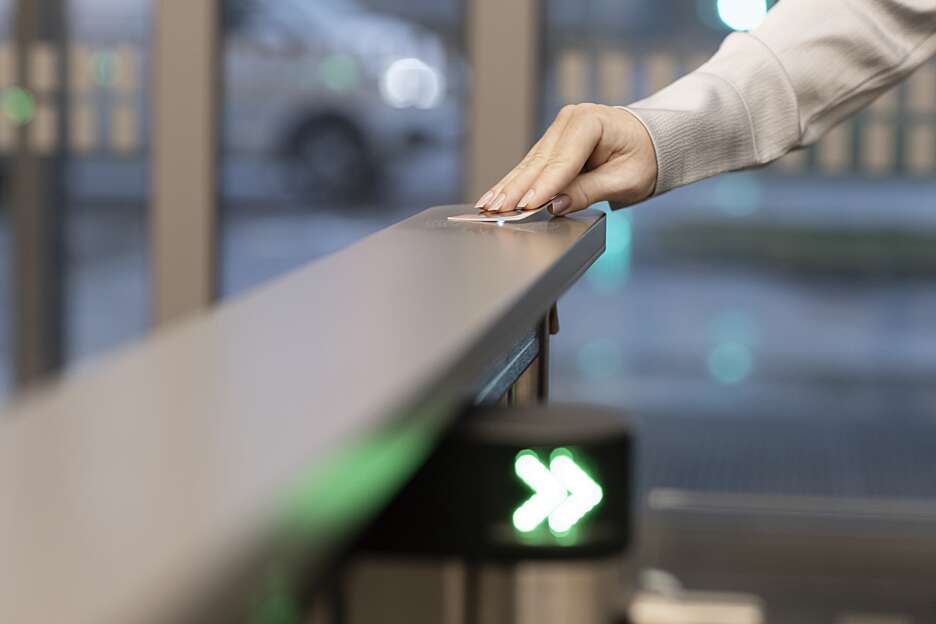 Person using an access card at an electronic access control system to enter a secure building.