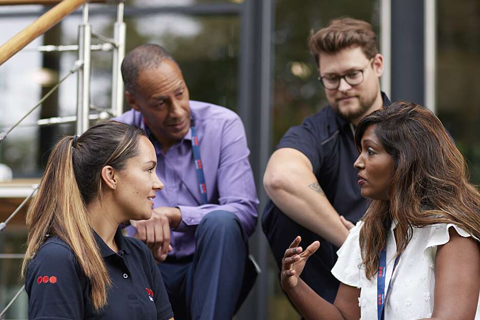 Four people sat talking outside an office building