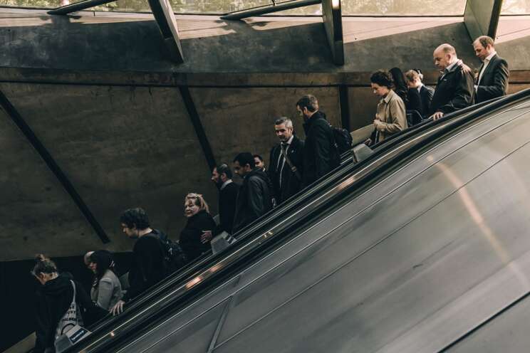 Ludzie na ruchomych schodach zjeżdżają do metra, podziemia.