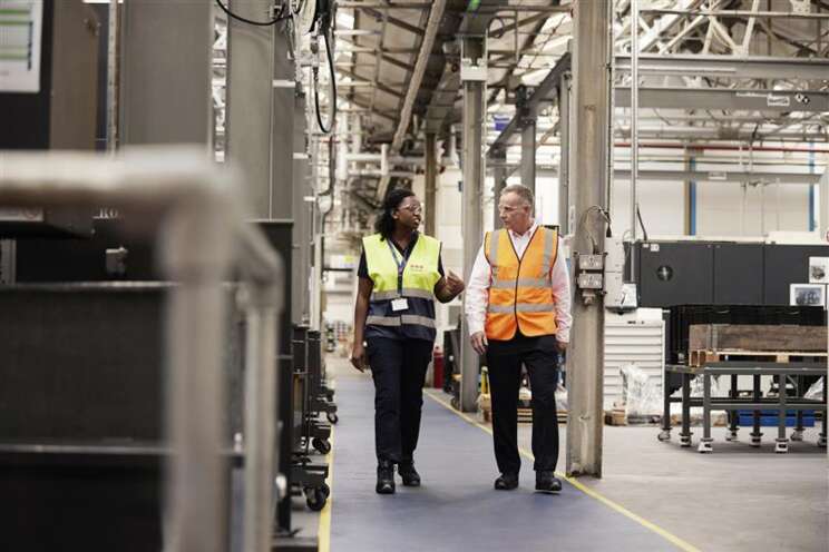 Securitas officer and staff in hi vis walking through indoor factory