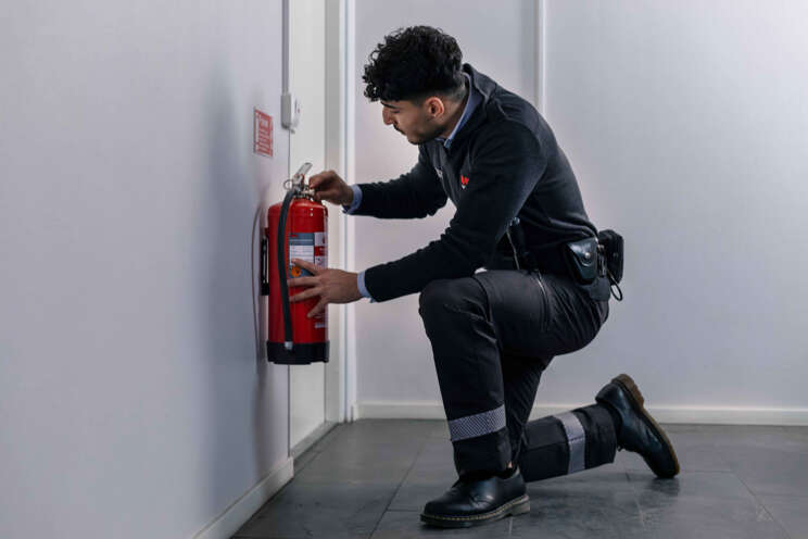 Arbeitsschutz, Fachkraft für Arbeitssicherheit bei der Wartung eines Feuerlöschers