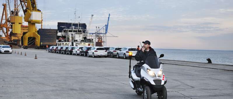 Kontrollant i hamnområde på moped pratar i walkie talkie
